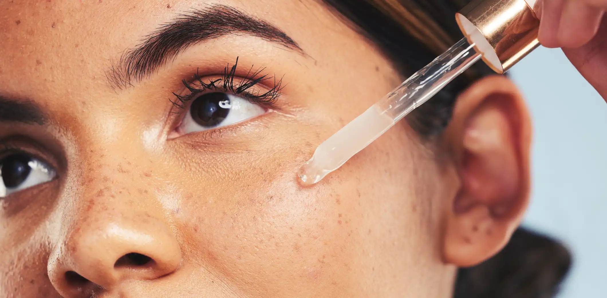 Junge Frau tröpfelt Glykolsäure Serum auf das Gesicht