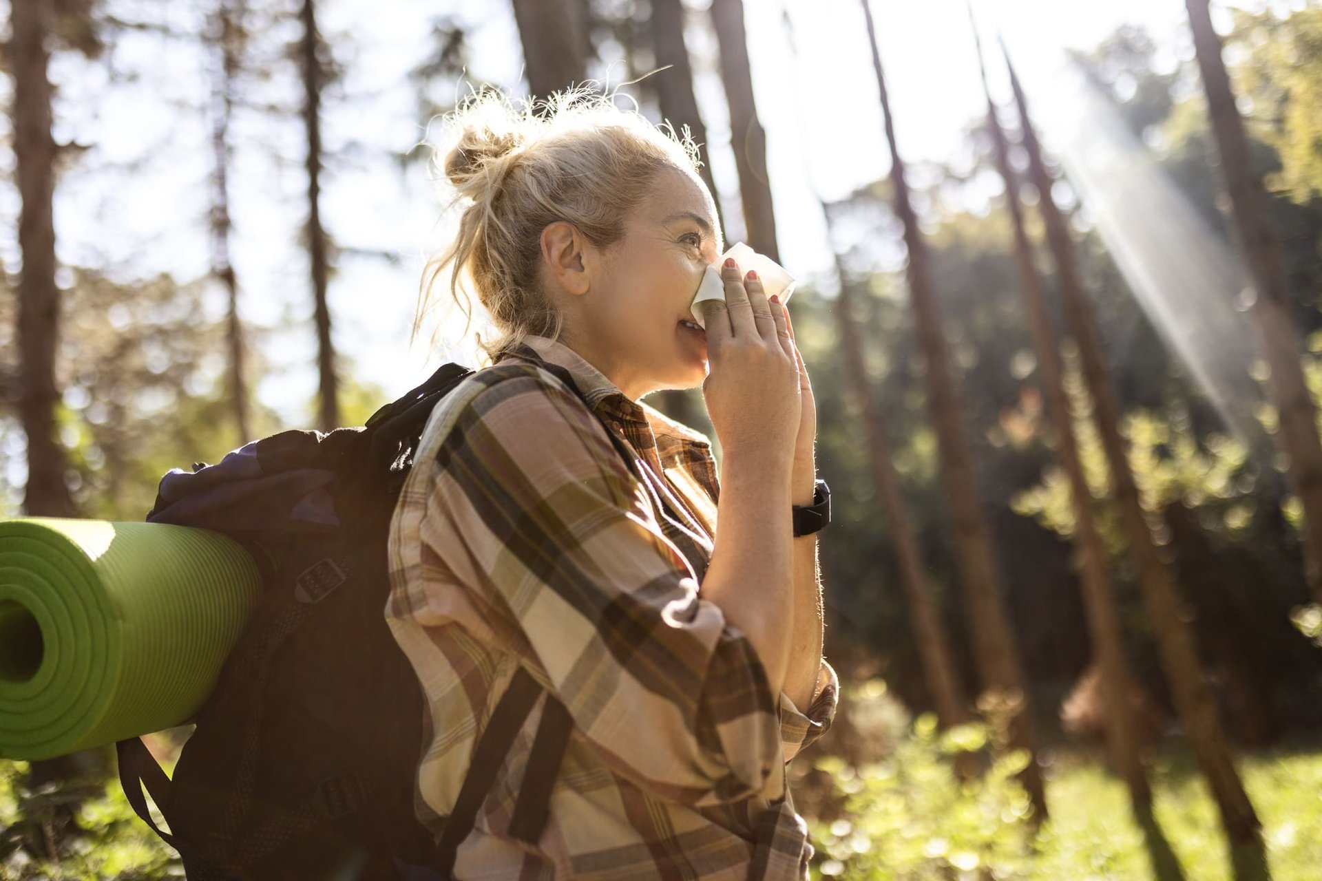 Frau geht durch den Wald und putzt sich ihre Nase