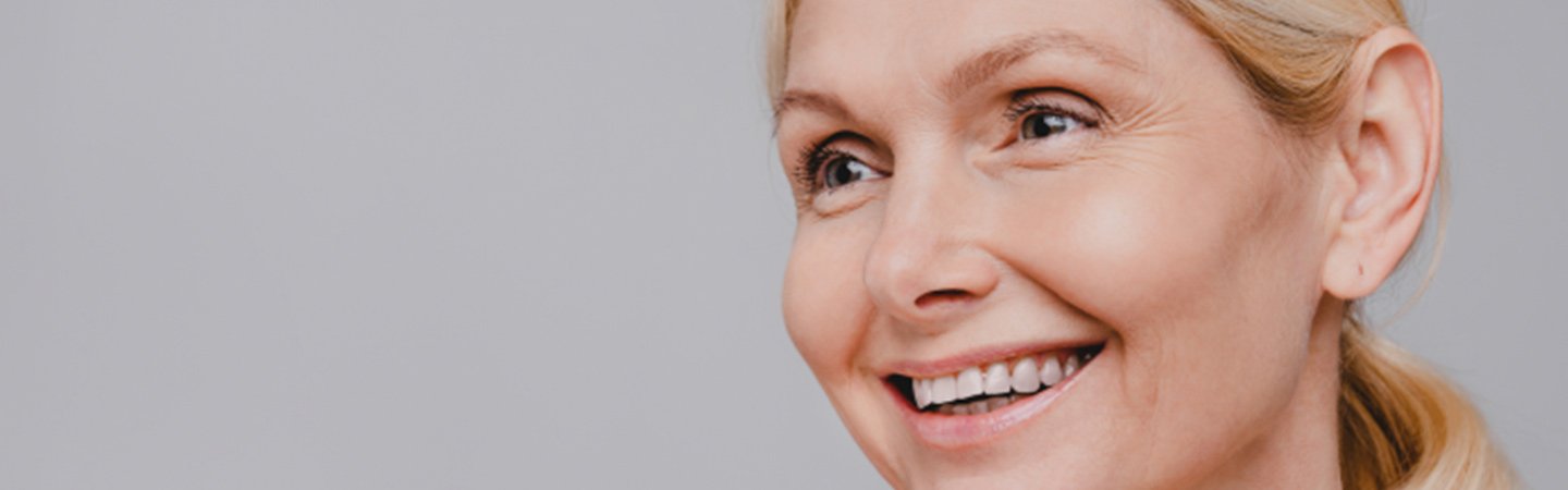 Frau mit Fältchen um die Augen lächelt und blickt zur Seite