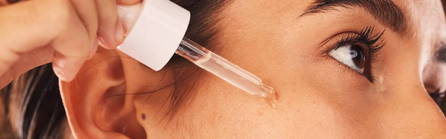 Une femme applique un sérum sur son visage couvert de grains de beauté