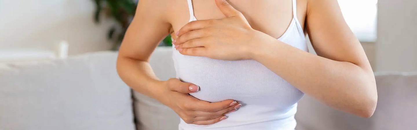Une jeune femme palpe ses seins pour détecter un cancer
