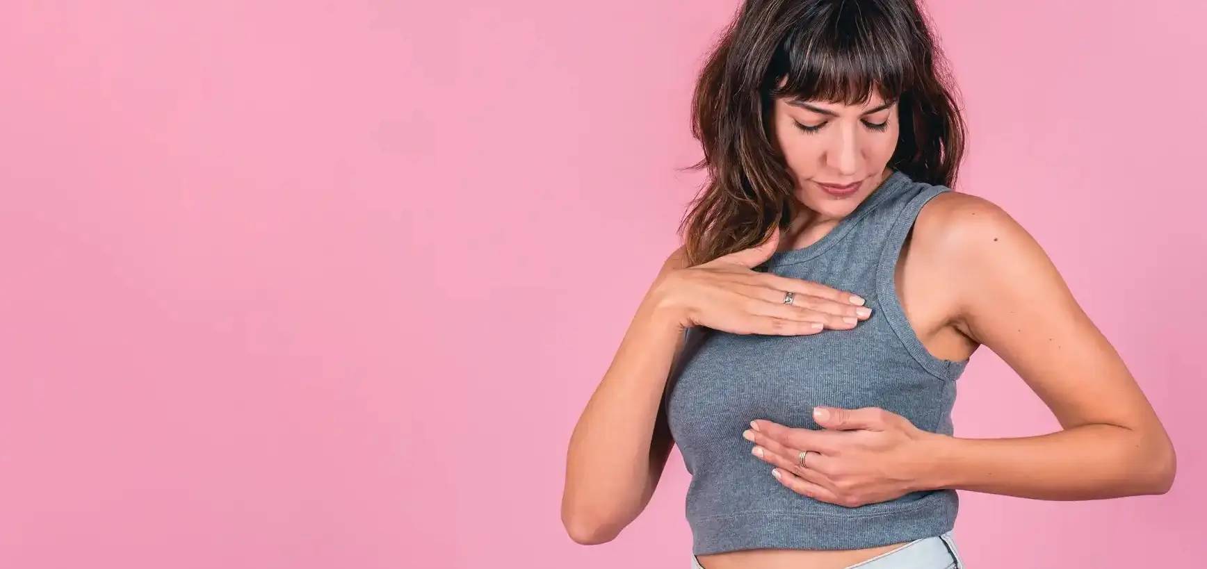 Une femme se palpe la poitrine : Cancer du sein : prévention et soins de la peau
