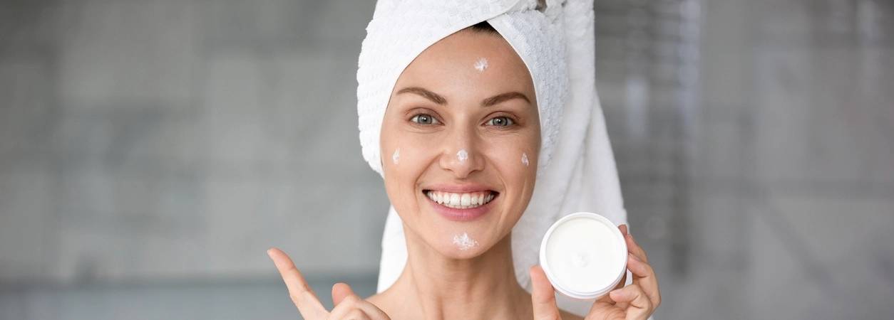 Une jeune femme applique une crème à l'acide hyaluronique sur son visage