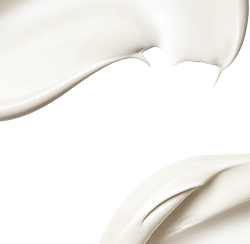 Nahaufnahme von weisser Creme, die geschmeidig und in geschwungenen Linien auf weißem Hintergrund verteilt ist.
