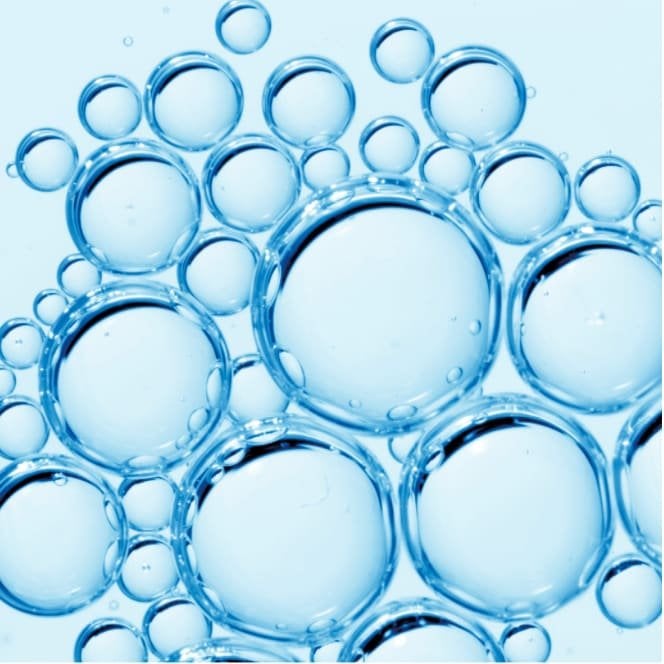 Nahaufnahme von klaren Flüssigkeitsblässchen auf blauem Hintergrund, welche den Inhaltsstoff LHA darstellen