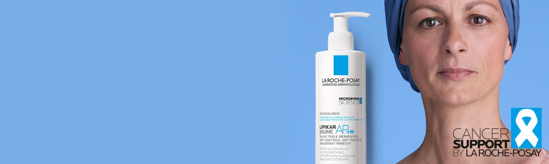 Flacon du produit Lipikar Baume AP+M de La Roche-Posay à côté d'une femme portant un foulard bleu devant un fond bleu, soutenu par la campagne « Cancer Support » avec le logo du ruban blanc.