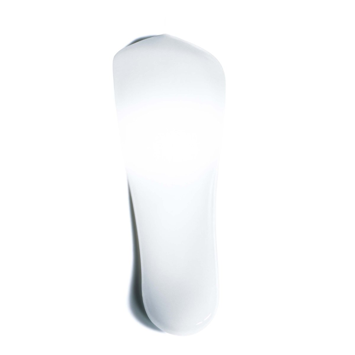 Une traînée blanche et allongée de crème sur fond clair. La texture semble lisse et légèrement brillante, comme un produit de soin pour la peau.